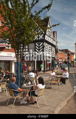 Regno Unito, Inghilterra, Warwickshire, Warwick, Market Place, Swan Street, diners al marciapiede tabelle nella luce del sole Foto Stock