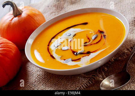 In casa cremoso ciotola di zuppa di zucca con freschi ingredienti vegetali su hessian, primo piano Foto Stock