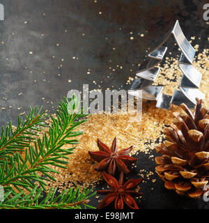 Natale biglietto di auguri sfondo con una formina a forma di albero di Natale con un ramo di pino, il cono, caramellato lo zucchero di canna e anice stellato spice su sfondo scuro con copyspace Foto Stock