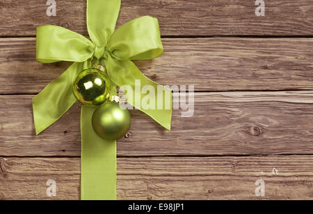 Decorativo arco verde decorato con due pallina Natale ornamenti su uno sfondo di legno con copyspace per il messaggio di saluto stagionale Foto Stock