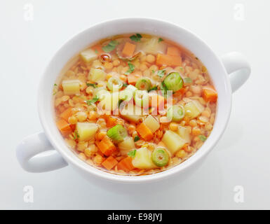 Sana tazza di lenticchie, la carota e la zuppa di porri ricco di proteine e fibra dietetica, ad alto angolo di visione su bianco Foto Stock