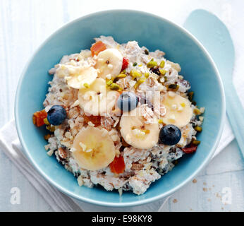 Vista aerea di una ciotola di cereali per la prima colazione e rabboccato con freschi e frutta secca tritata e i pistacchi Foto Stock