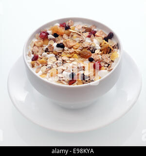 Ciotola di deliziosa prima colazione con muesli e avena fiocchi di grano miscelato con frutta secca e noci servita in un bianco vaso in ceramica per Foto Stock