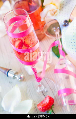 Elegante champagne flute riempito con champagne e fragole su un tavolo decorativo in una celebrazione Foto Stock