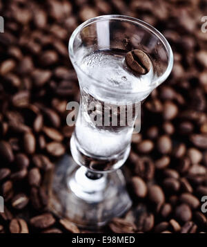 Cancellare il caffè sambuca in un bicchiere alto circondato da fagioli non macinati Foto Stock