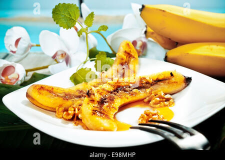Deliziosa golden brown grigliate di banana e noce dessert servito su un piatto bianco Foto Stock