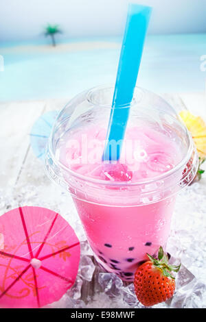Deliziosa miscelate bolle di fragola tè con bacche servita con un cocktail di rosa parasol su una terrazza che si affaccia sull'oceano Foto Stock