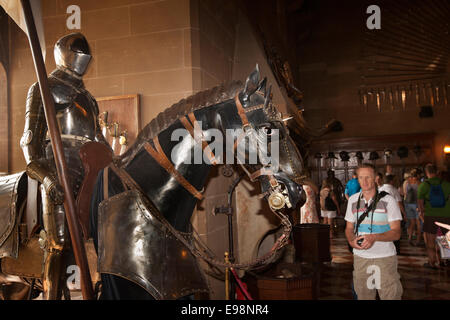 Regno Unito, Inghilterra, Warwickshire, il Castello di Warwick, visitatore nel grande salone guardando a cavallo corazza Foto Stock