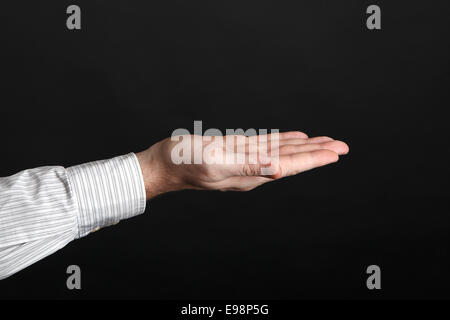 Maschio caucasico tenere le mani qualcosa di fronte a uno sfondo nero Foto Stock