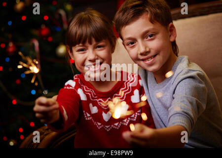 Ritratto di felice fratelli con luci di Bengala a celebrare il Natale Foto Stock