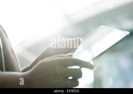 Donna che utilizza un tablet PC contro la luce diretta del sole Foto Stock