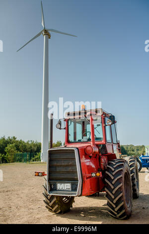 Raro 4x4 rosso Massey Ferguson trattore gigante con turbina eolica in cantiere su un luminoso giorno di sole, la rivista del coperchio anteriore Foto Stock