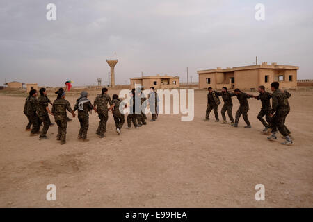 Combattenti curdi delle unità di protezione del popolo YPG e femmina Combattenti delle unità di protezione delle donne YPJ che eseguono un tradizionale Danza curda in un campo di allenamento in al Hasakah o. Distretto di Hassakeh nel nord della Siria Foto Stock