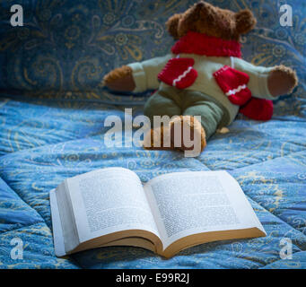 Libro in brossura aperto sul letto con Teddy bear Foto Stock