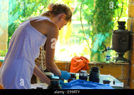 Ragazza ottiene pattern sul tessuto vernice in un workshop rurale Foto Stock