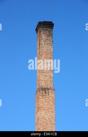 Uno arancione mattone tubo sul cielo blu. Foto Stock