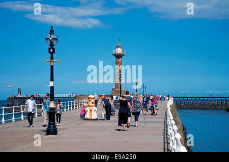 Persone visitatori turisti che camminano sul West Pier in estate Whitby Seafront Harbour North Yorkshire Inghilterra Regno Unito Gran Bretagna Foto Stock