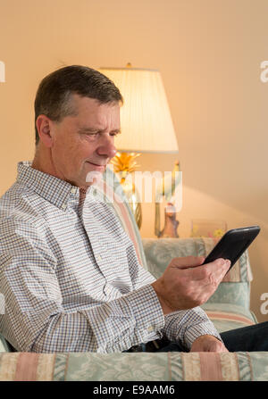 Senior uomo la lettura di eBook sul lettino Foto Stock