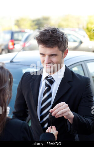 Affascinante venditore dando un cliente le chiavi dell'auto Foto Stock