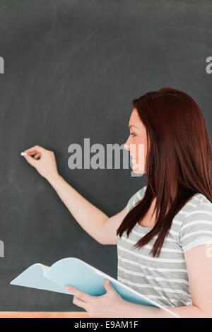 Focalizzato giovane donna di scrittura su una lavagna Foto Stock