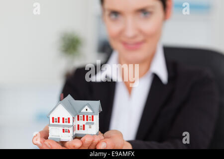 Imprenditrice tenendo una casa in miniatura Foto Stock
