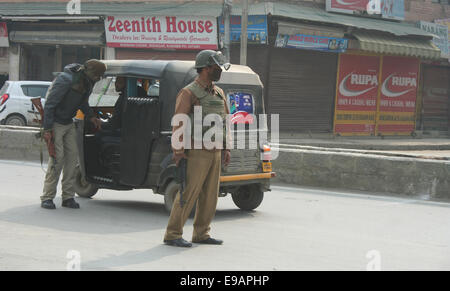 Srinagar, Indiano Kashmir amministrato. 23 ottobre, 2014. Un poliziotto indiano controlla i passeggeri veicoli durante un giorno di sciopero come negozi e imprese è rimasta chiusa nel Kashmir a causa di un separatista sponsorizzato sciopero per protestare per una visita alla regione da parte del Primo Ministro Narendra Modi Credito: Sofi Suhail/Alamy Live News Foto Stock