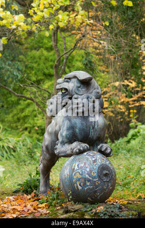 Cinese cane pippo statua in bronzo a Batsford Arboretum in autunno. Moreton-in-Marsh, Gloucestershire, Inghilterra Foto Stock
