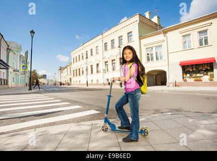 Ragazza asiatica con i capelli lunghi si erge su uno scooter Foto Stock