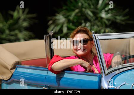 Donna matura seduto al volante di un open-sormontato classic car, sorridente Foto Stock