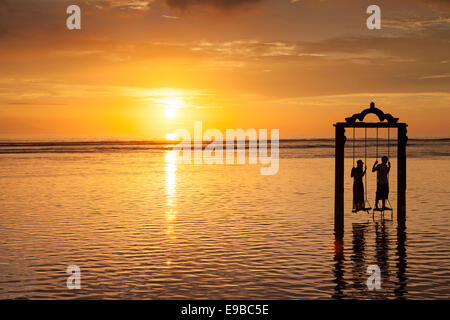 L uomo e la donna sul mare swing al tramonto, 'Gili Trawangan', 'isole Gili', Indonesia Foto Stock