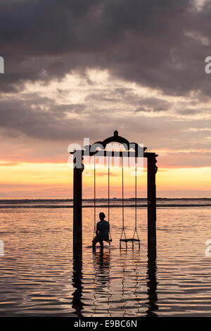 Donna seduta su mare swing al crepuscolo, 'Gili Trawangan', 'isole Gili', Indonesia Foto Stock