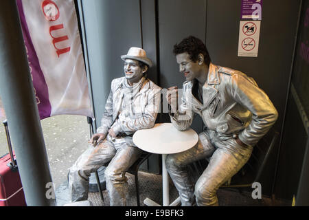 Stand Still, immobile, gli artisti di strada / esecutori avente un periodo di riposo e relax tempo prendendo una pausa al bar, coffee shop,Parigi. Foto Stock