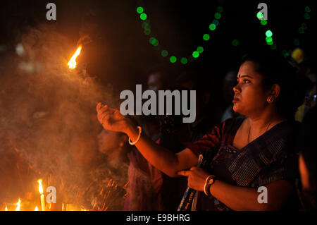 Dacca in Bangladesh. 23 ott 2014. Le donne pregare alla Dea Kali con il fuoco. "Kali Puja' è un festival dedicato alla dea Indù Kali durante la luna nuova giornata nel mese indù. Maithili lo chiamano "hyama Puja' o Diwali. Credito: Mohammad Asad/Pacific Press/Alamy Live News Foto Stock