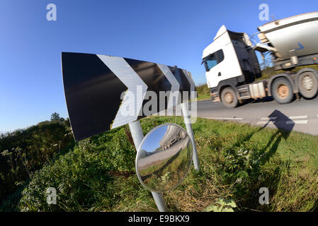 Autocarro passando un cartello di segnalazione della curva circolare e specchio di sicurezza per dare piloti emergenti dalla vista svincolo stradale del Regno Unito Foto Stock