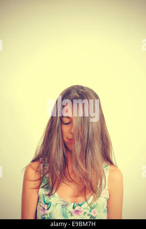 Ritratto di una giovane donna bruna con i suoi capelli nel suo viso e gli occhi chiusi, con un effetto retrò Foto Stock