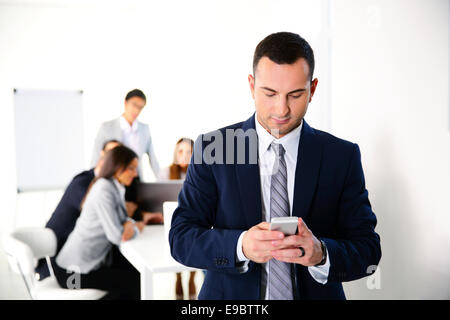 Imprenditore utilizza lo smartphone nella parte anteriore del business meeting Foto Stock