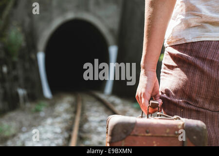 Donna e vintage valigia su strada ferrata e tunnel. Foto Stock