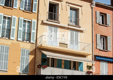 Balconi e finestre con tendine di case color pastello nella città Saint-Tropez lungo la Riviera Francese, Var, Francia Foto Stock