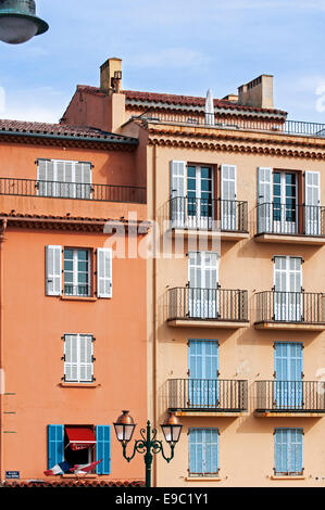 Balconi e finestre con tendine di case color pastello nella città Saint-Tropez lungo la Riviera Francese, Var, Francia Foto Stock