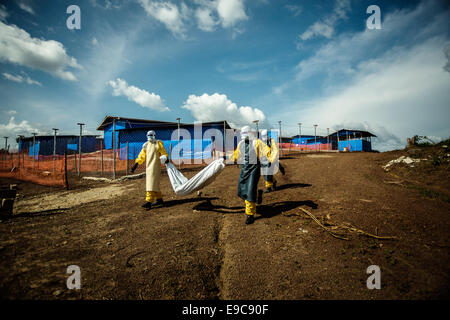 Lavoratori volontari indossando indumenti di protezione rimuovere il corpo di una vittima di Ebola in un villaggio Ottobre 8, 2014 in Suakoko, Liberia. Foto Stock