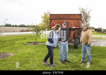 Tre gli agricoltori al di fuori di parlare e di ridere Foto Stock
