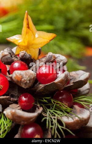 Pigna decorata con mirtilli rossi come albero di Natale, circondato da verde ghirlanda di Natale Foto Stock