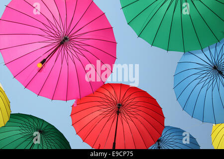 Raccolta di multi ombrelloni colorati appesi in una posizione aperta su una strada che offrono ombra e protezione dagli elementi Foto Stock