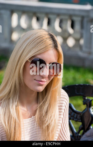 Giovane donna bionda indossando occhiali da sole nel parco Foto Stock