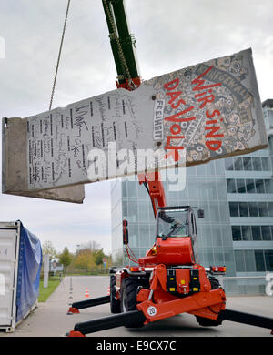 Leipzig, Germania. 25 ott 2014. Una gru solleva un tratto del muro di Berlino in Leipzig, Germania, 25 ottobre 2014. Il gas naturale azienda Verbundnetz Gas AG (VNG) navi il suo pezzo di muro, che fu acquistato nel 2009, a Washington. Esso sarà consegnato a motivo dell'Ambasciata di Germania nel corso di una cerimonia che si terrà il 13 novembre 2014. Il pezzo è stato dipinto da un artista di Lipsia e porta signitures di varie personalità di spicco come l'ex cancelliere tedesco Kohl e ex noi Secretarie di stato Kissigner e Baker. Foto: Hendrik Schmidt/dpa/Alamy Live News Foto Stock