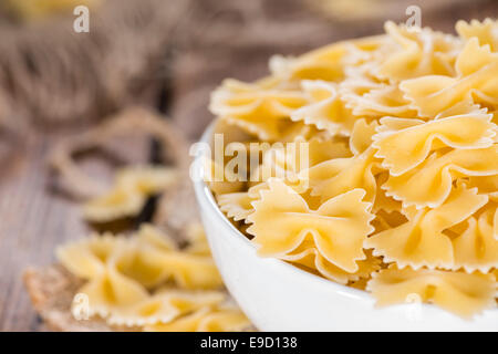 Farfalle (comunemente noto come pasta Bow-Tie) in una ciotola su sfondo di legno Foto Stock