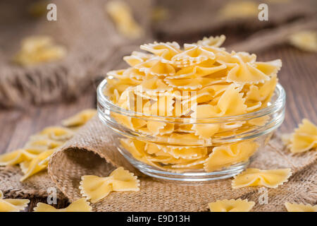 Farfalle (comunemente noto come pasta Bow-Tie) in una ciotola su sfondo di legno Foto Stock