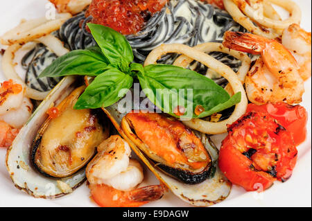 Pasta di colore nero con frutti di mare e basilico Foto Stock