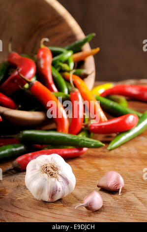 Una composizione di peperoncini rossi su una tavola di legno Foto Stock