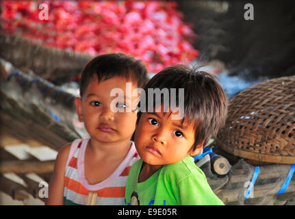 Due giovani cambogiani che devono aspettare mentre le loro madri Ha lavorato sorting e asciugando peperoni rossi in Cambogia Foto Stock